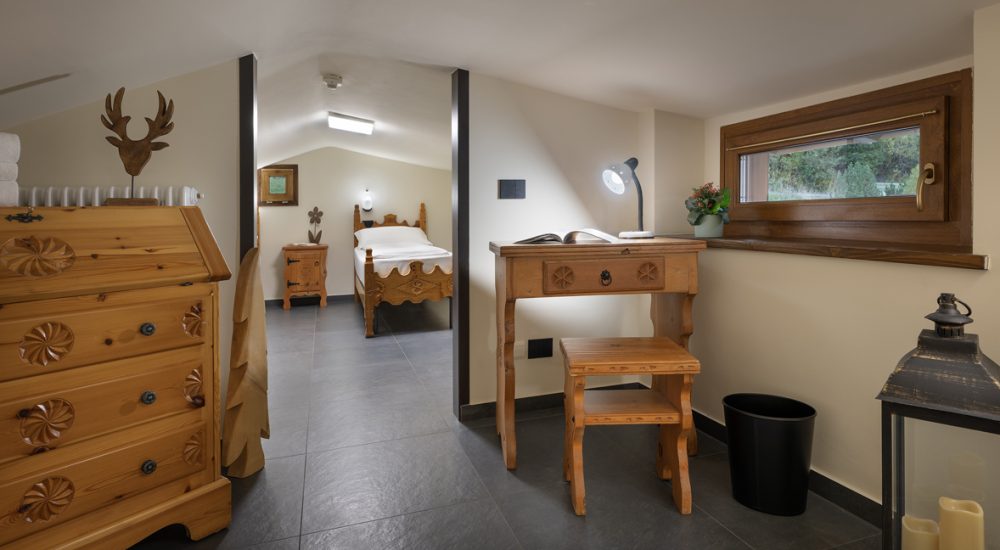 Rustikales Schlafzimmer mit Holzmöbeln und einer Lampe auf dem Schreibtisch neben dem Fenster.