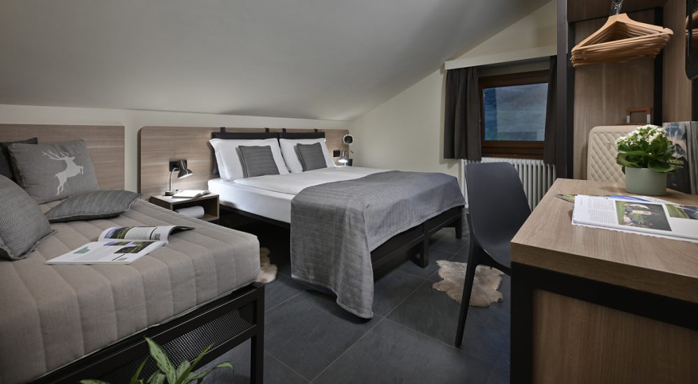 Ein modernes und gemütliches Hotelzimmer mit zwei Betten, einem Schreibtisch und schlichter Einrichtung.