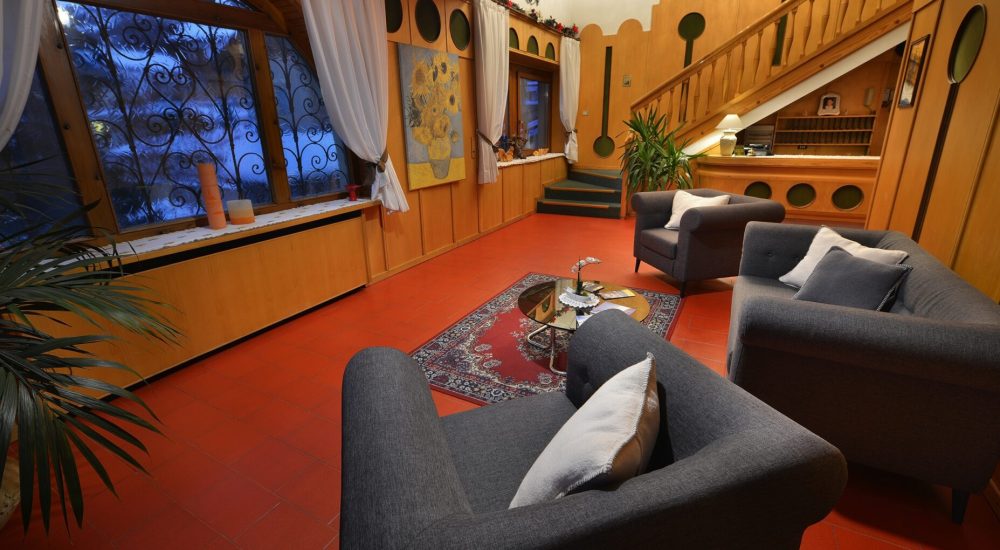 Lounge-Bereich eines Hotels mit Holzmöbeln, grauen Sofas und einem roten Teppich.