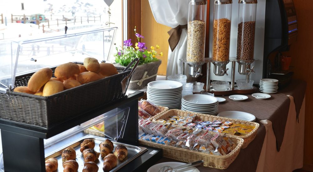 Frühstücksbuffet mit Brot, Croissants, Müsli und verschiedenen Aufstrichen.