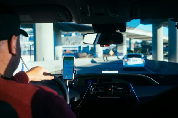Autista che guida in autostrada con navigatore GPS su smartphone.
